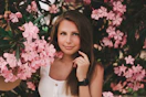 woman wearing white sleeveless top besides pink flowers