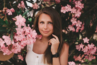 woman wearing white sleeveless top besides pink flowers
