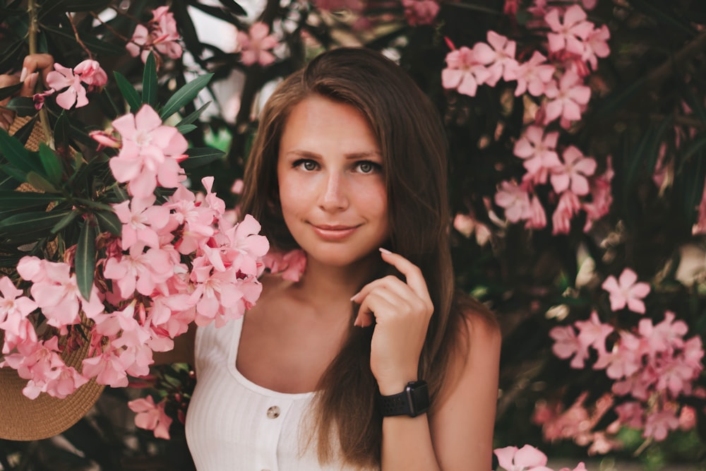 woman wearing white sleeveless top besides pink flowers