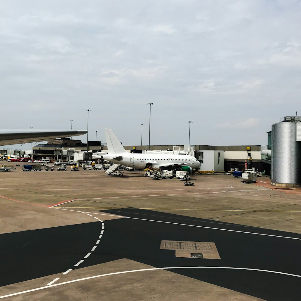 white airplane parked near stainless steel tanks