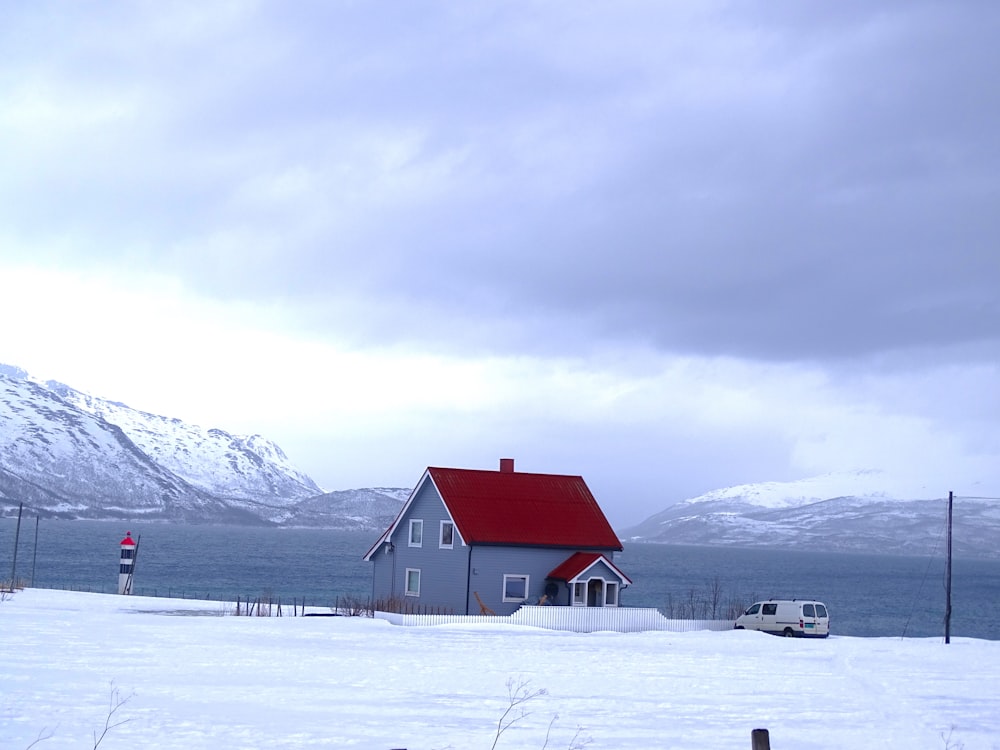 gray and red house near body of water and mountains