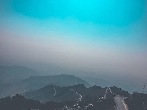 A vibrant photo of a winding mountain road under a clear blue sky.
