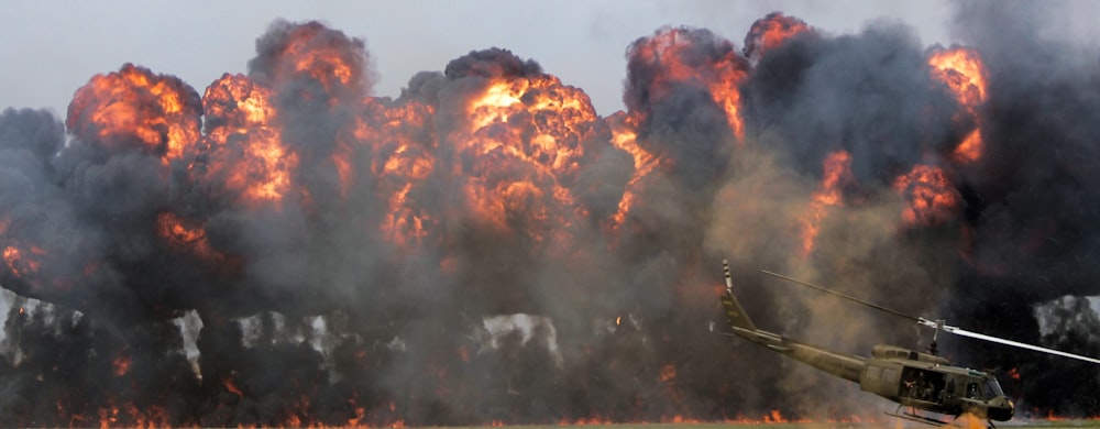 Grüner Hubschrauber in der Nähe eines großen Feuers