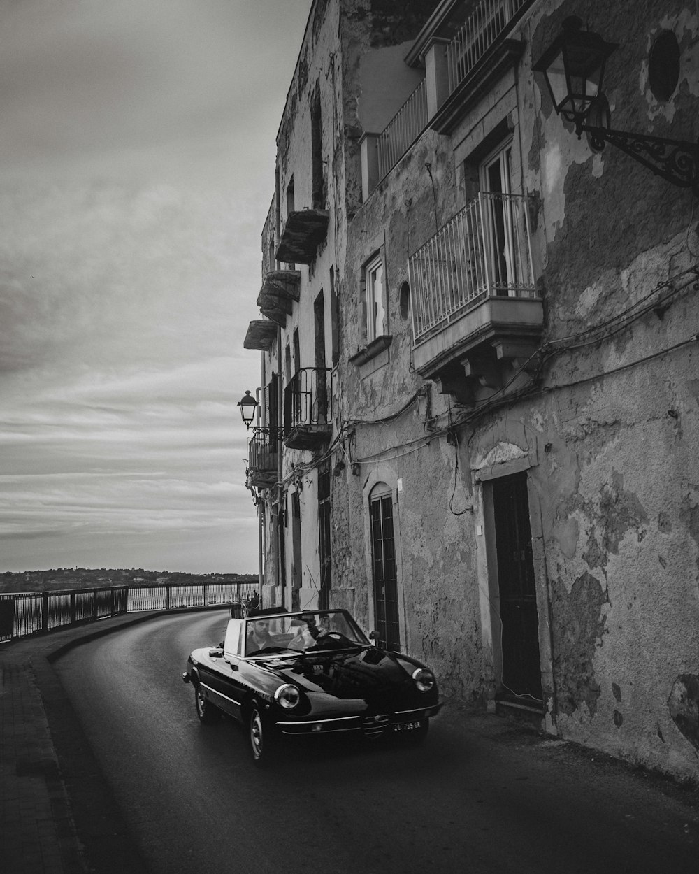 grayscale photo of car beside building