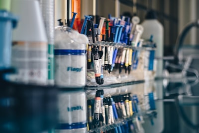 assorted-color syringes on clear glass rack chemistry teams background