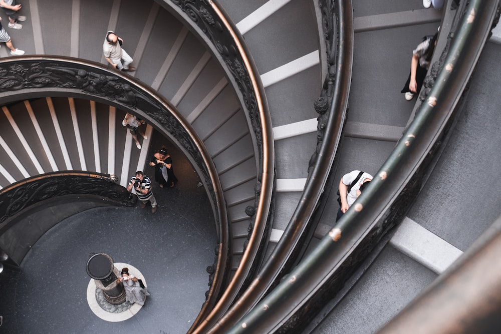 top-view photography of people walking down on spiral stairs