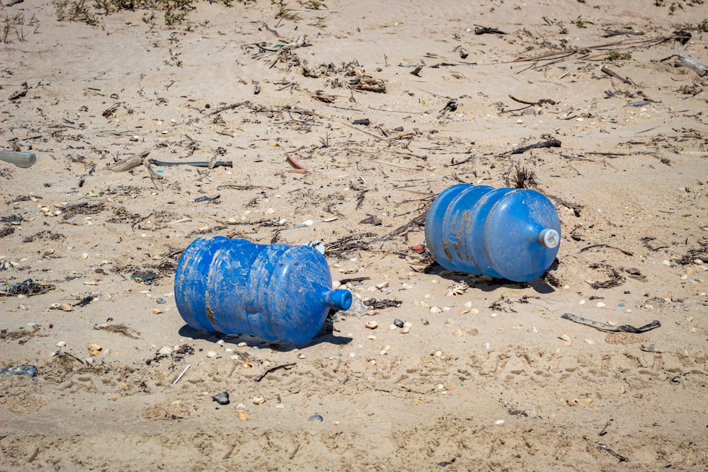 two blue plastic carboys on seashore