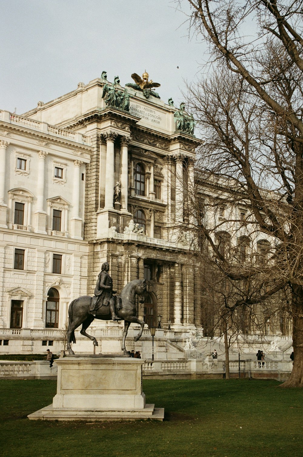 낮에는 흰색 콘크리트 건물 앞에서 말 동상을 타고 있는 남자