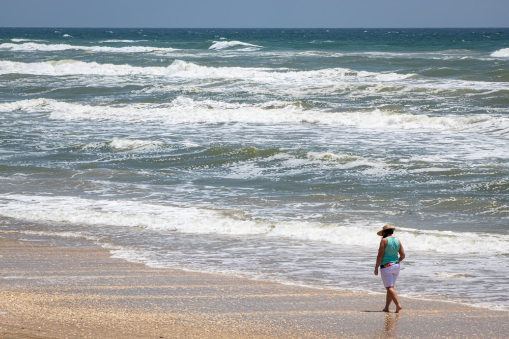 Mann in Grün geht am Strand spazieren