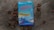 A book titled 'Misteri Soliter' by Jostein Gaarder is placed on a wooden surface surrounded by dried brown leaves. The book cover is predominantly blue with red and yellow text. It features an illustration of architectural structures and a sky with balloons.