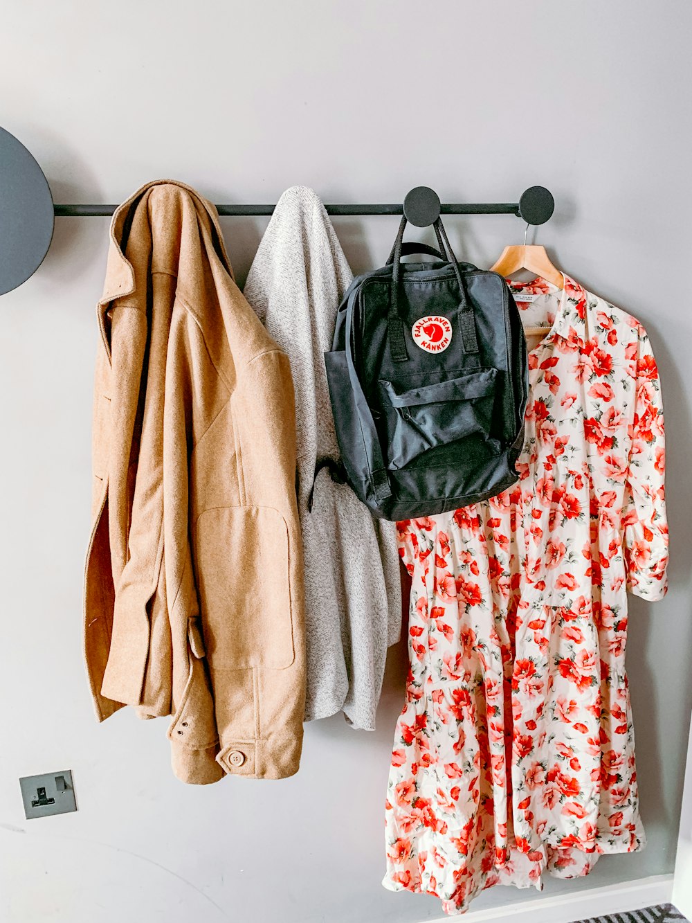 coat, sweater, backpack, and floral dress hanging on wall hanger