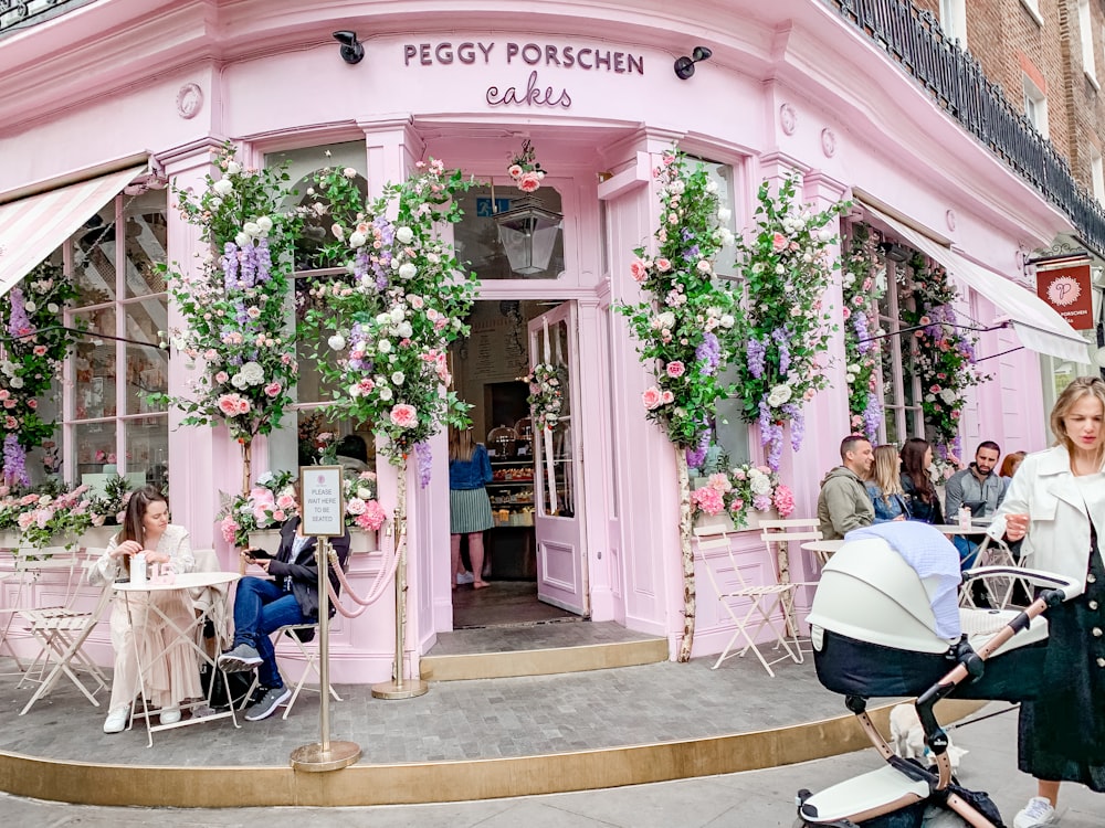 woman holding black and white bassinet stroller standing in front of Peggy Porschen Cakes building