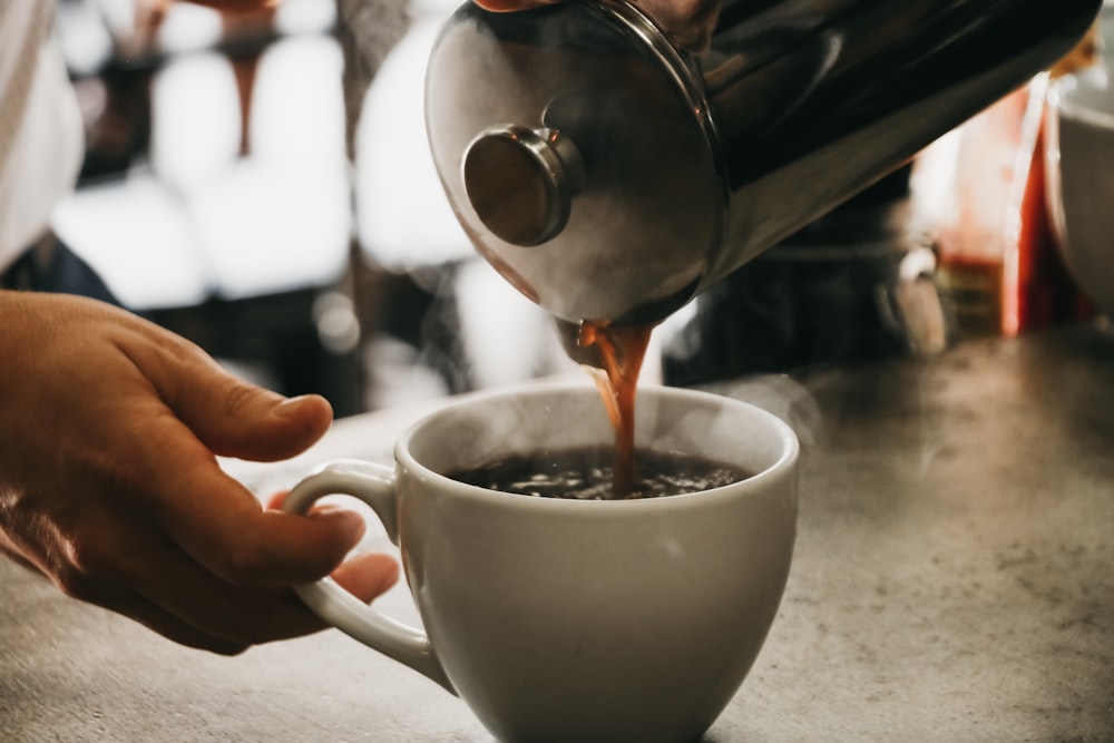 person pouring coffee in white ceramic cup