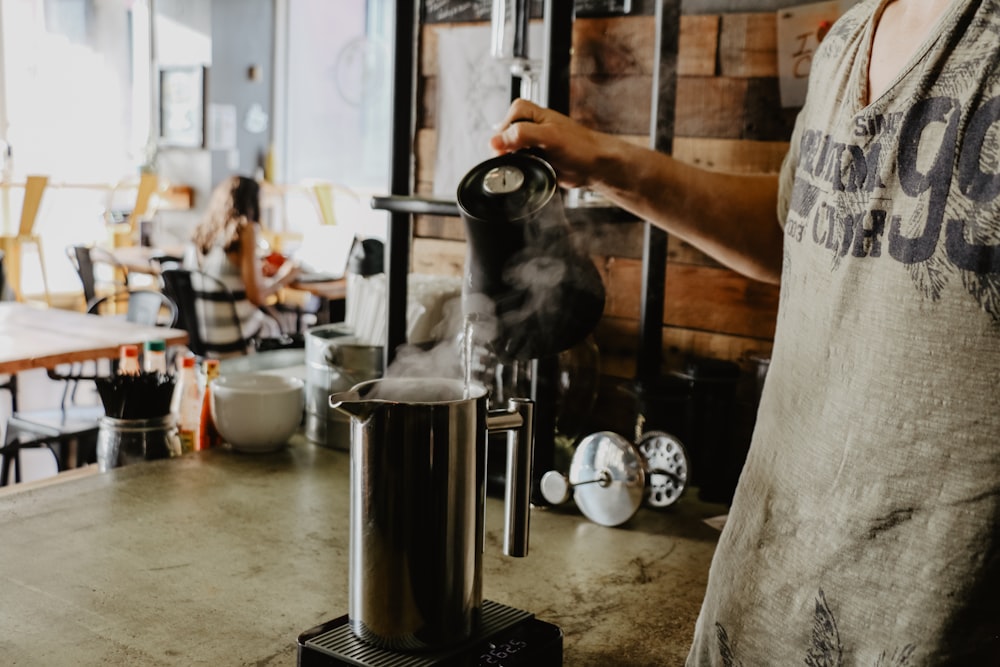 man holding black electric kettle