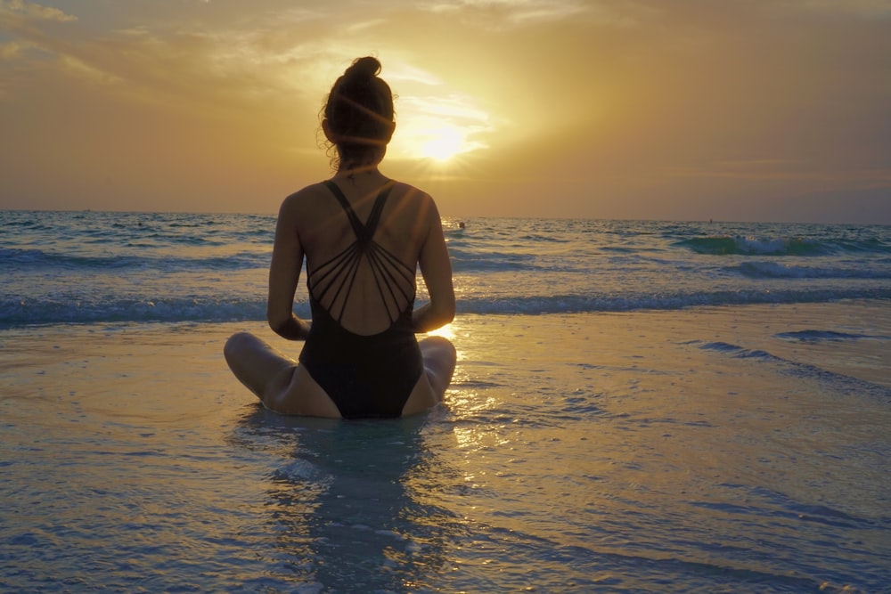 woman sitting on shore during golden hour