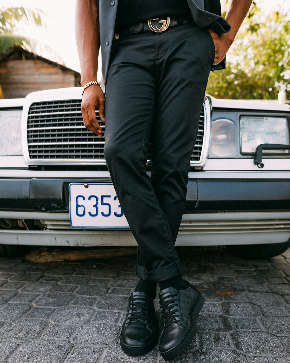 person wearing black dress pants leaning on black vehicle