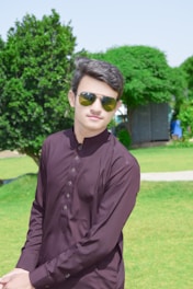 Indian man confidently sporting trendy grey sunglasses outdoors in bright sunlight.