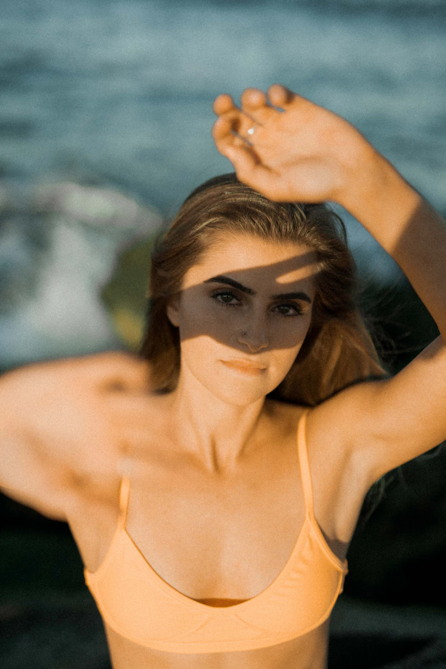 Woman shielding her face from the sun, film-grain editorial portrait