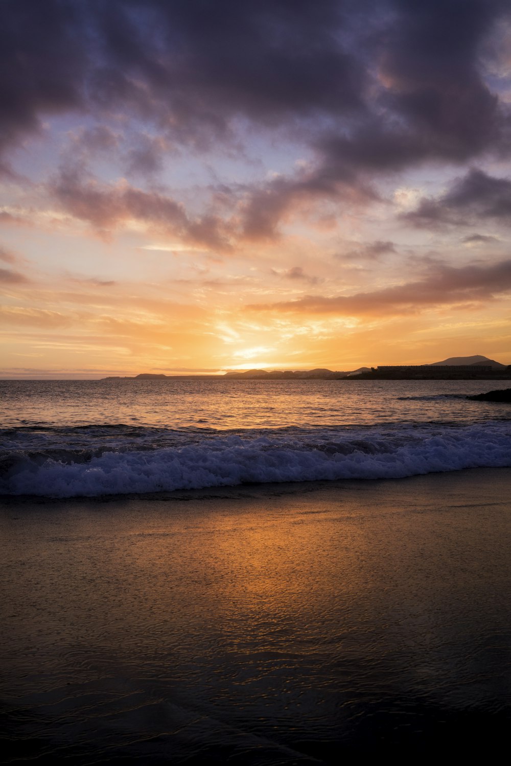 the sun is setting over the ocean on a cloudy day