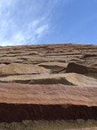 Photo of a bricklayer carefully building a sturdy wall under bright daylight.