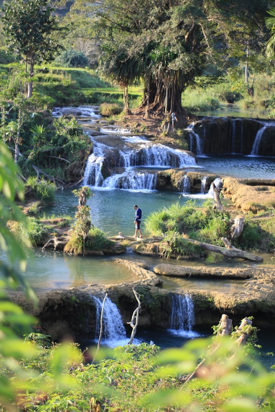 person standing on rock at river during daytime in Sumba Indonesia