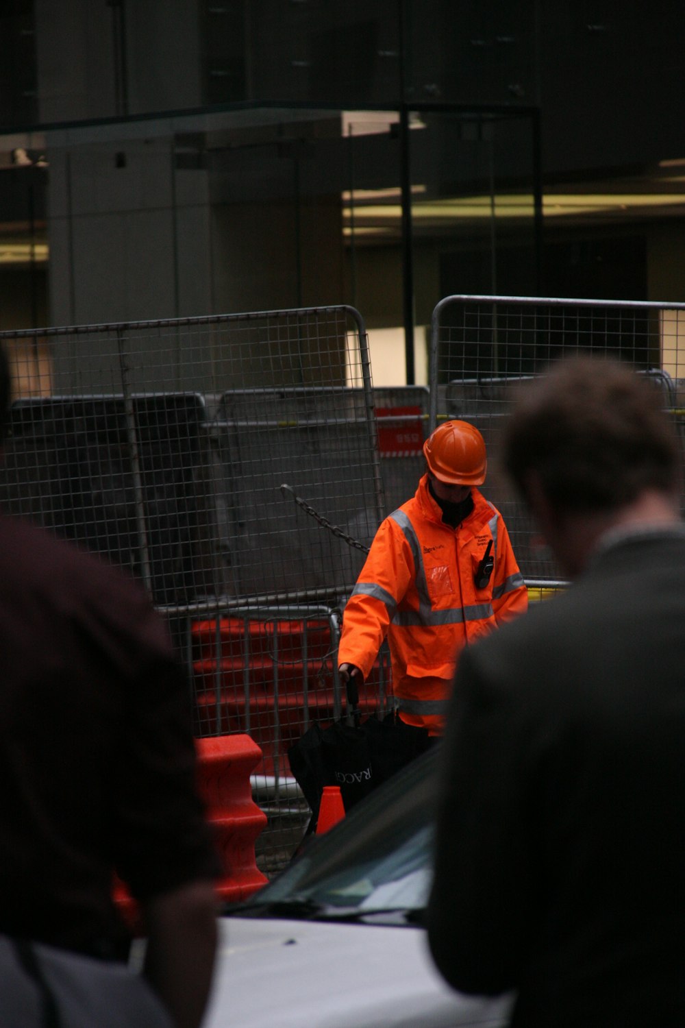 man wearing reflective suit standing beside link fence