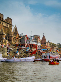 Boats on the Ganges river before stone ghats and temples in Varanasi, India