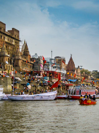 Boats on the Ganges river before stone ghats and temples in Varanasi, India