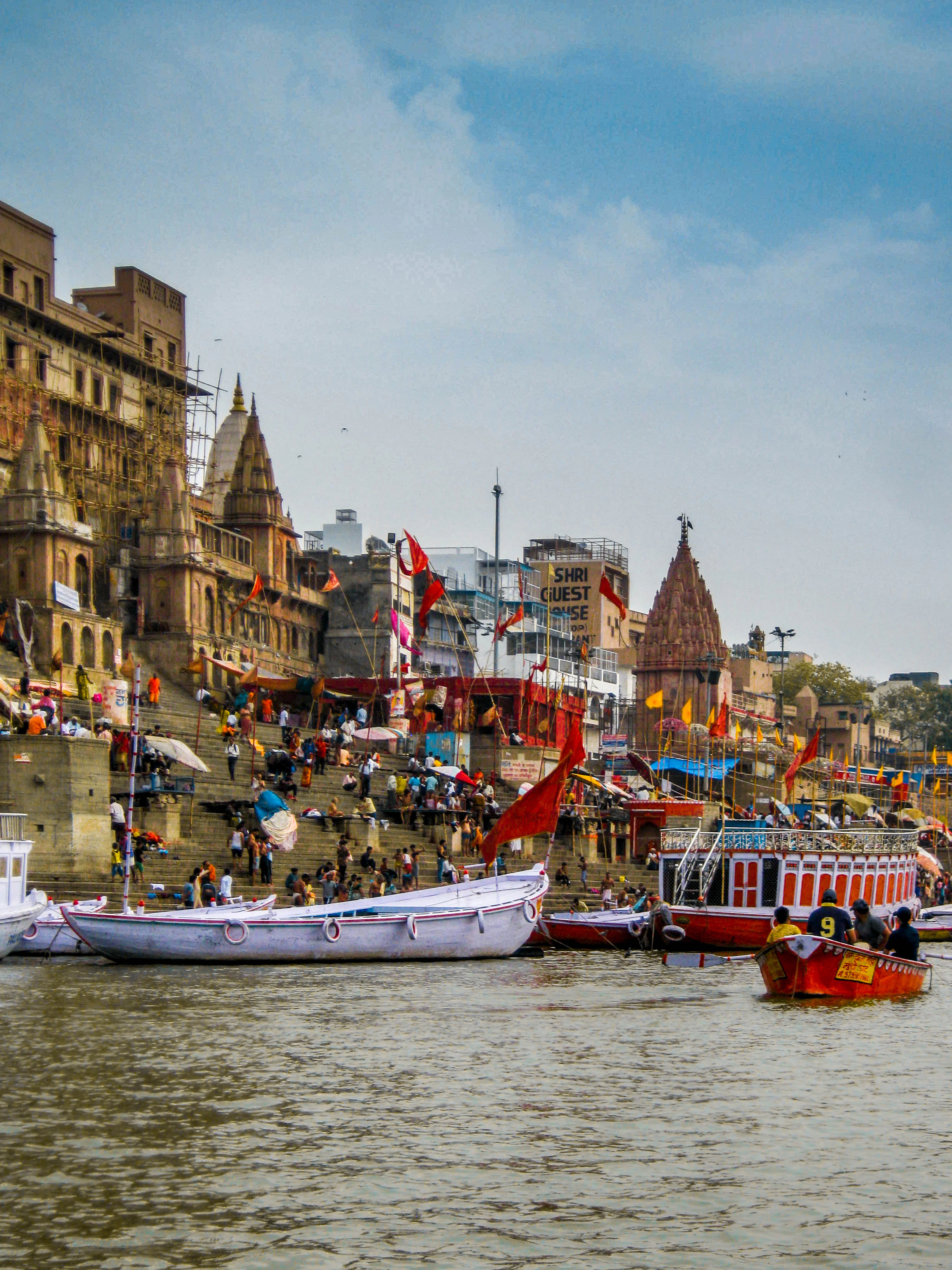 Boats moored below the tiered stone ghats and temples of Varanasi on the Ganges