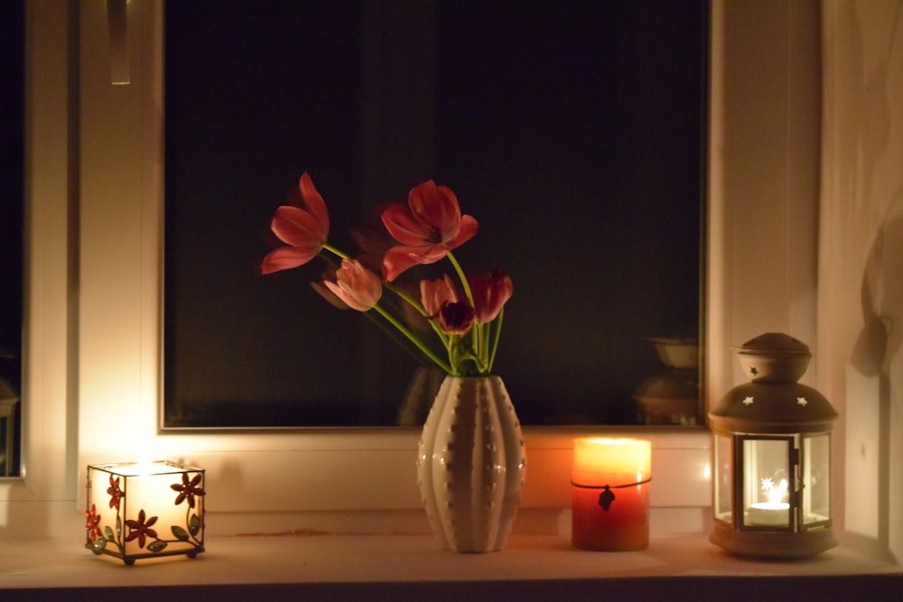 pink petaled flowers near lamps and candles