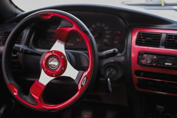 Bright customized steering wheel cover in black and red leather fitted neatly in a sports car.