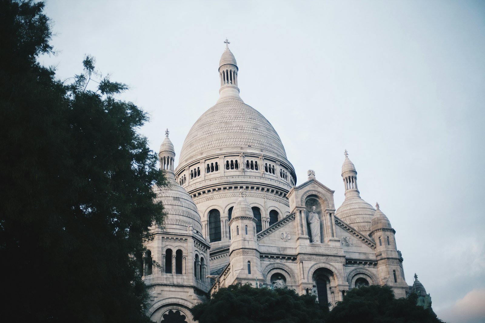 The white domes of the Sacré-Cœur Basilica rising beside dark trees on the hill of Montmartre