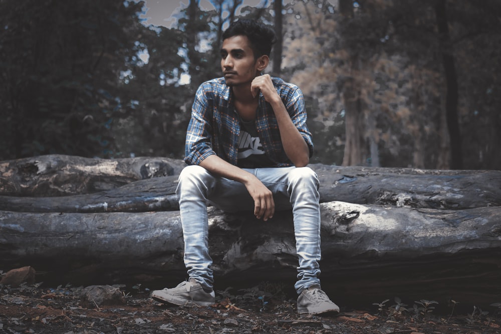 man wearing sport shirt sitting on log