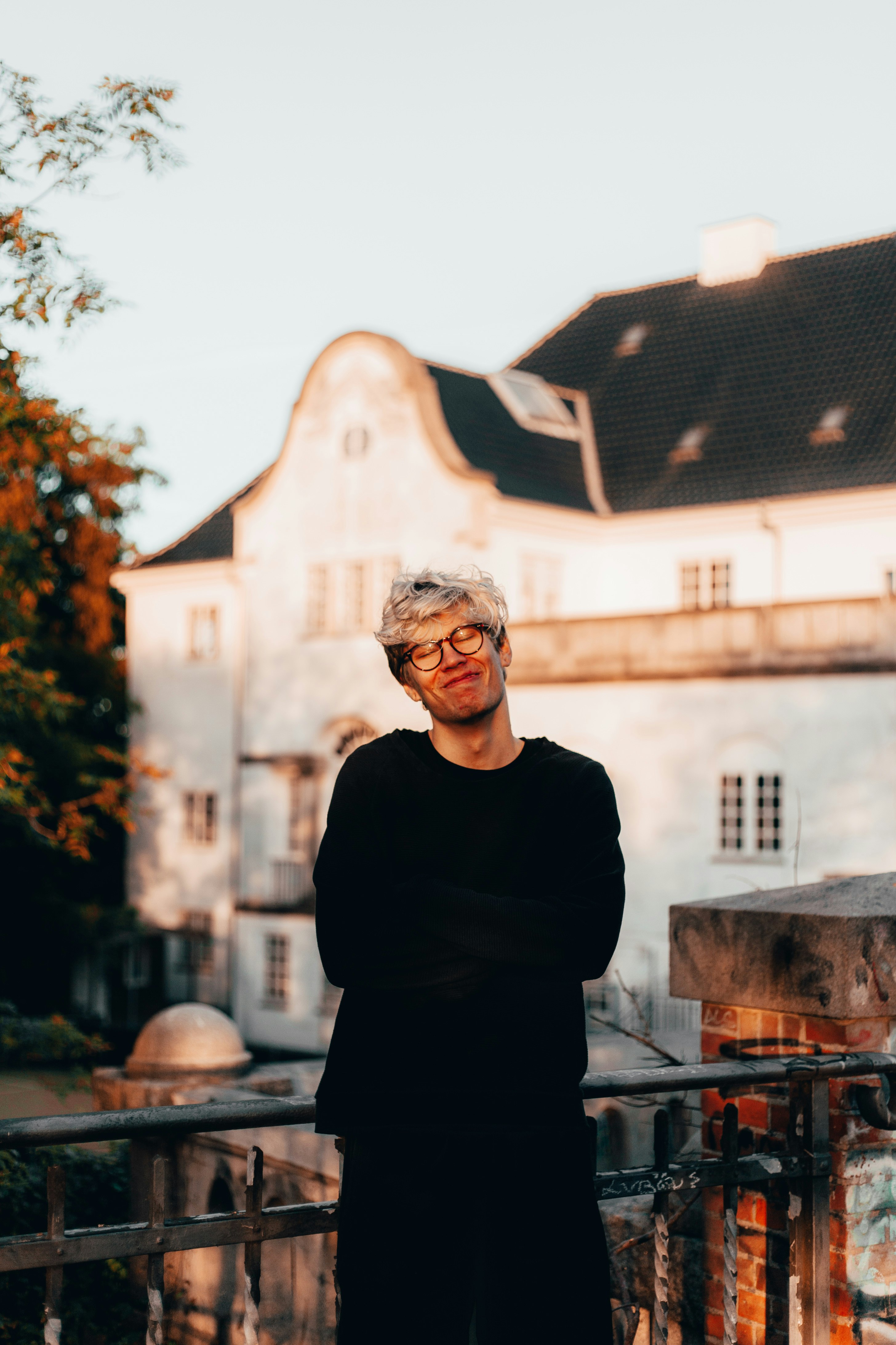 man wearing black crew-neck shirt standing beside gray concrete building