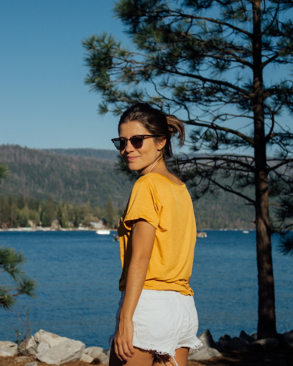 smiling woman standing near tree and body of water