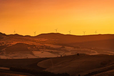 A scenic wind farm with turbines spinning gently against a sunset.