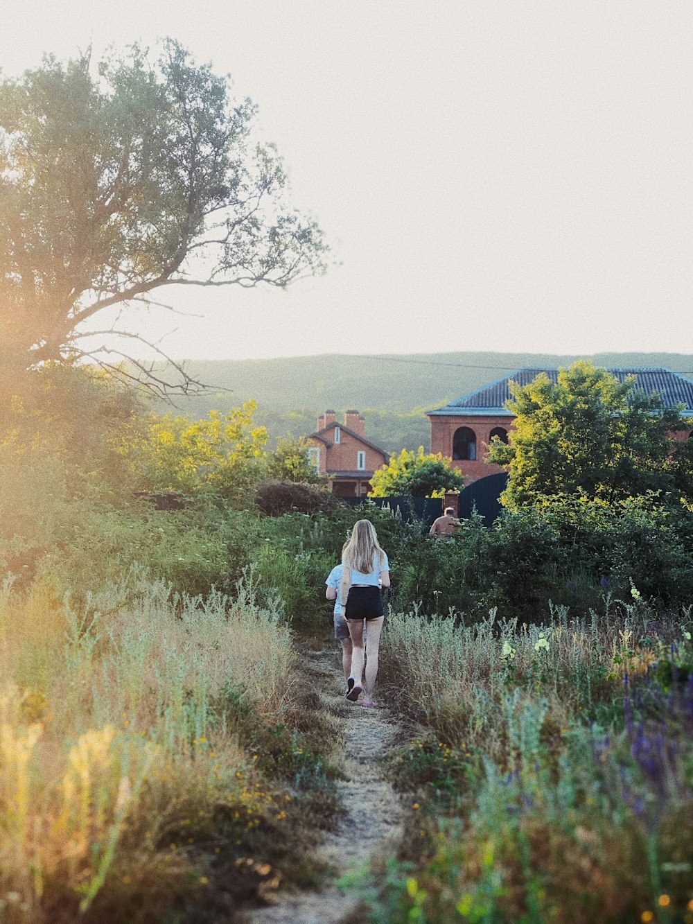 woman walking on grass field under white sky