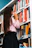 woman wearing pink shirt in front of bookshelf