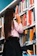 woman wearing pink shirt in front of bookshelf