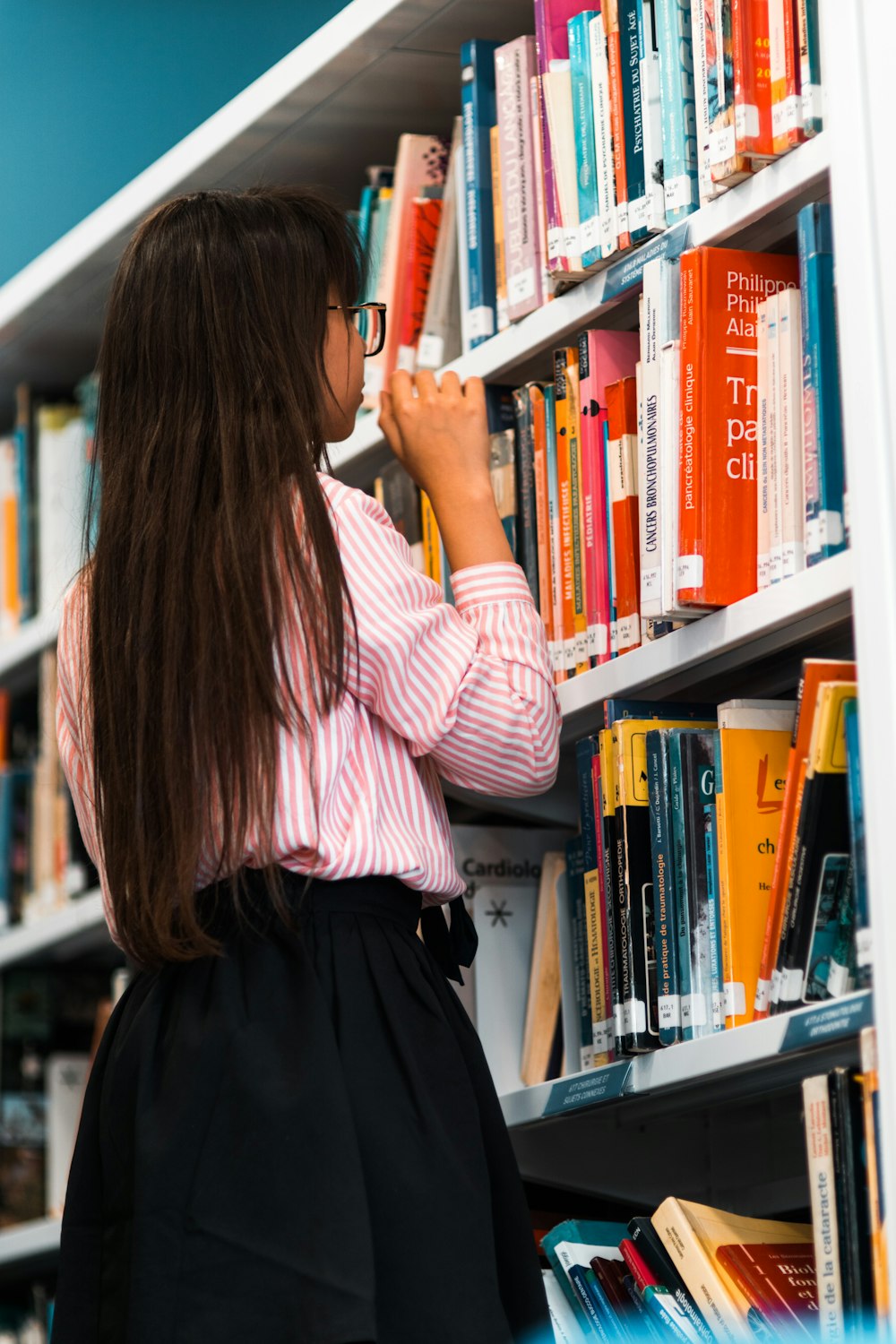 woman wearing pink shirt in front of bookshelf