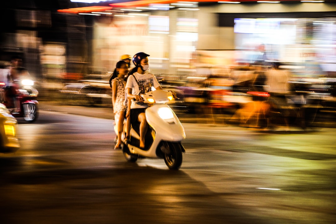 time lapse photography of three people riding a motor scooter