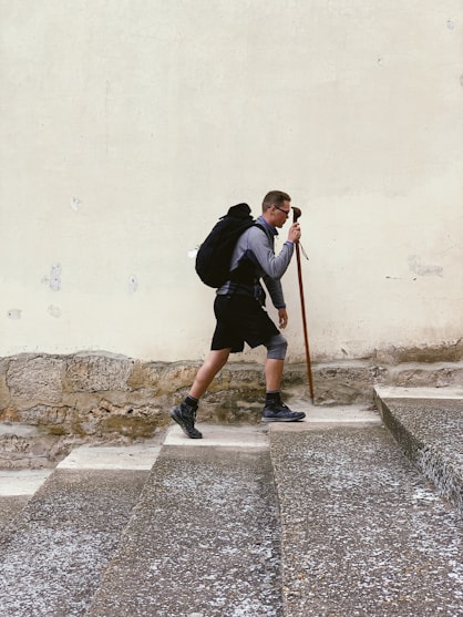 man walking on stairs while holding walking cane