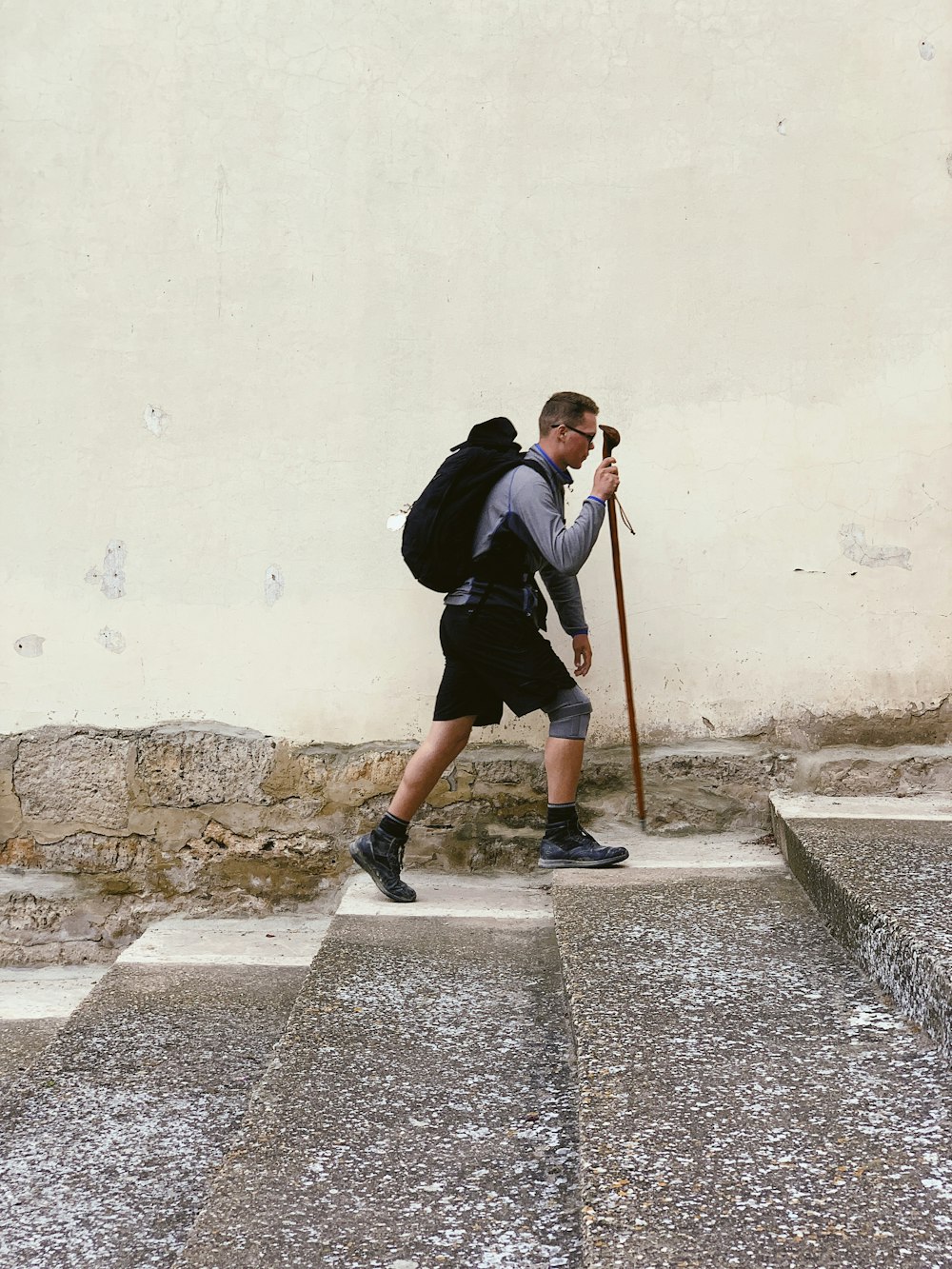 man walking on stairs while holding walking cane