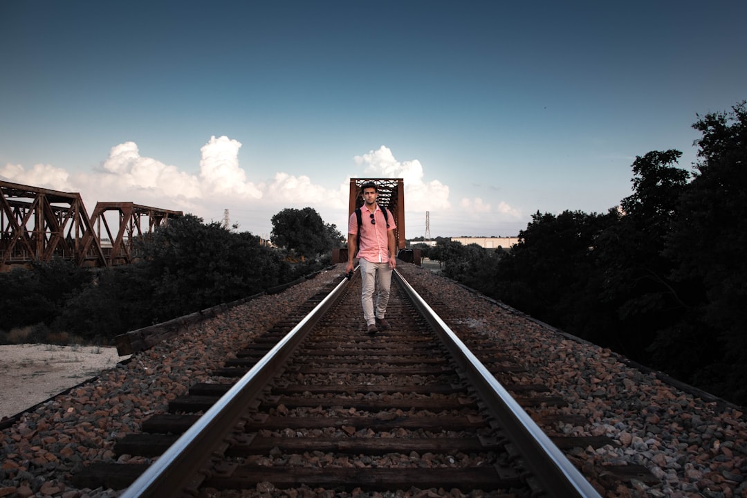 man walking on train tracks during daytime