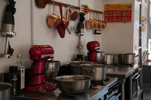 A sleek professional kitchen setup with stainless steel equipment and vibrant orange accents.