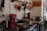A kitchen setup with various cooking appliances and utensils neatly arranged. There are red stand mixers on the counter alongside several stainless steel pots and pans. Above the counter, copper utensils and scoops are hung on a rack. Bottles of olive oil and black pepper are also visible. The environment looks organized and ready for cooking.