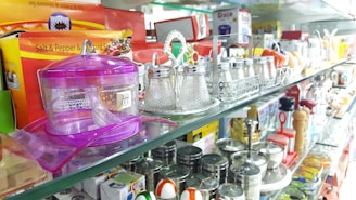 A collection of gift items and plastic containers displayed on a bright shelf.