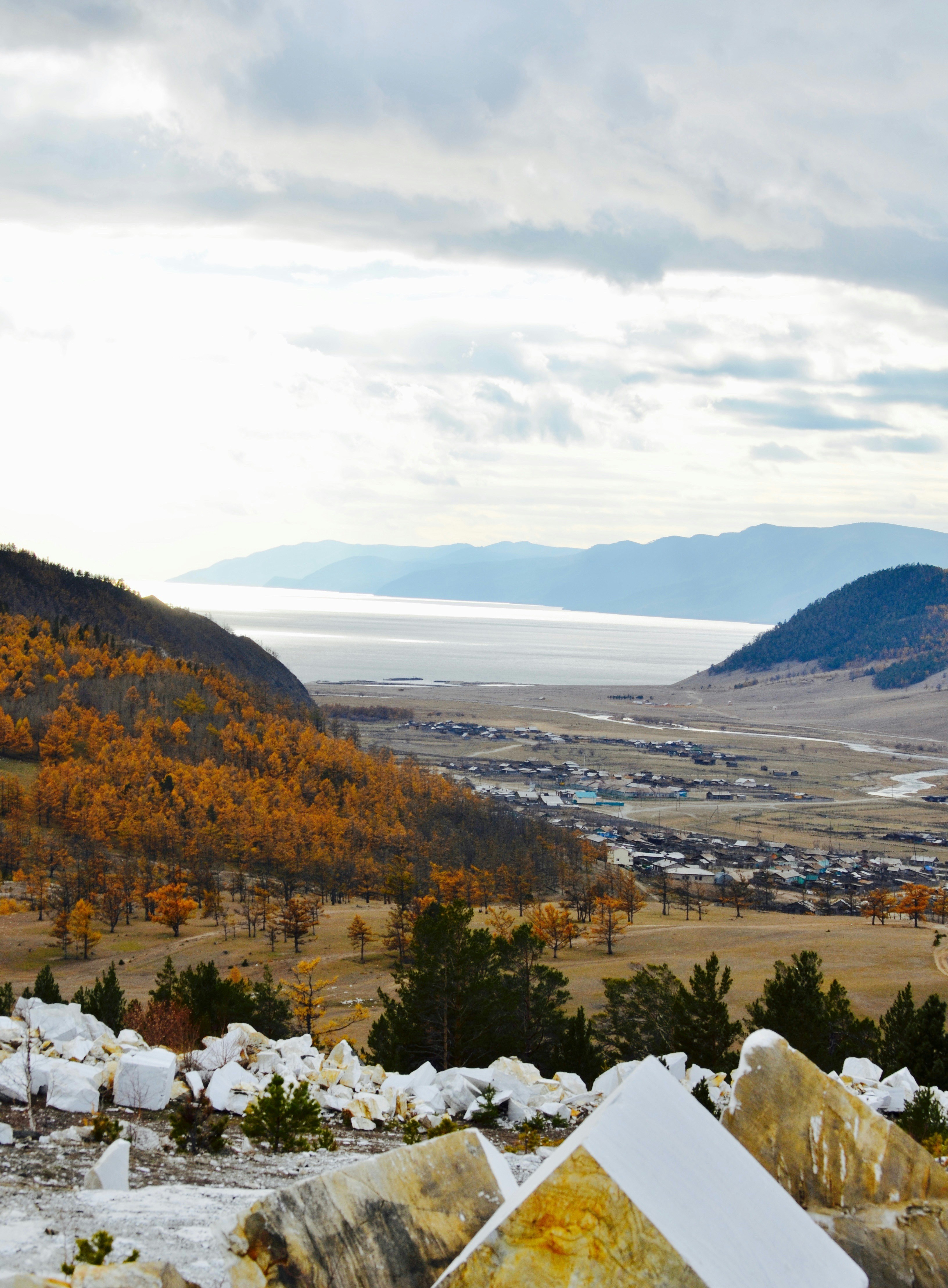 Häuser in der Nähe des Feldes mit Blick auf Berg und Meer unter weißem und grauem Himmel