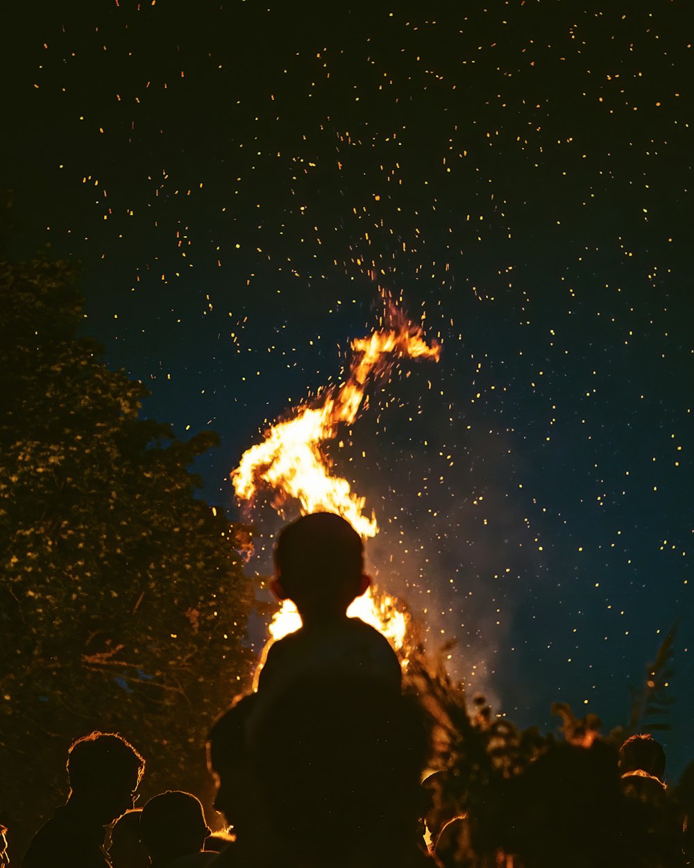 silhueta de pessoas olhando em chamas sob noite estrelada