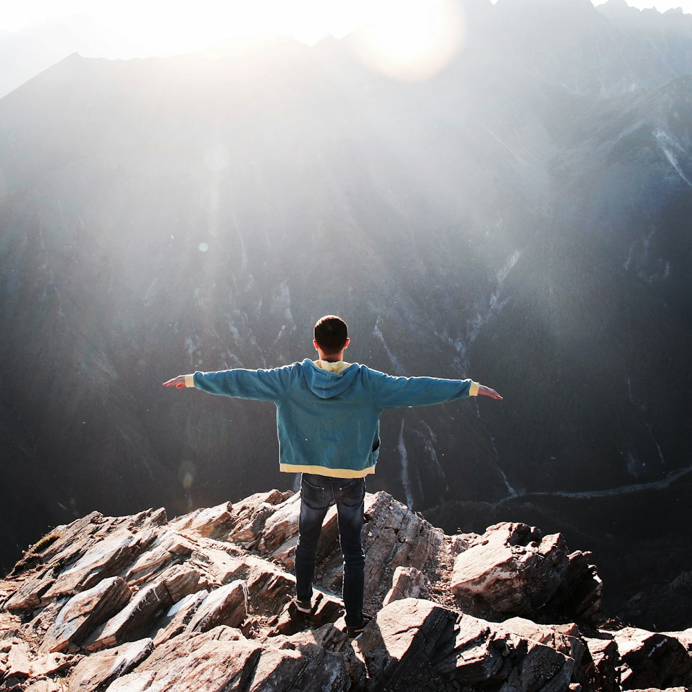 man wearing blue jacket standing on cliff